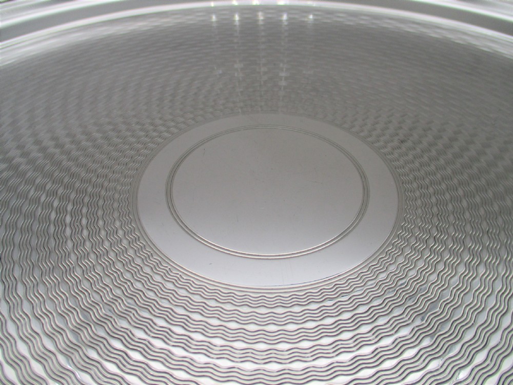 A round silver-plated cocktail tray with engine-turned concentric patterning and an unengraved central circular cartouche. View V