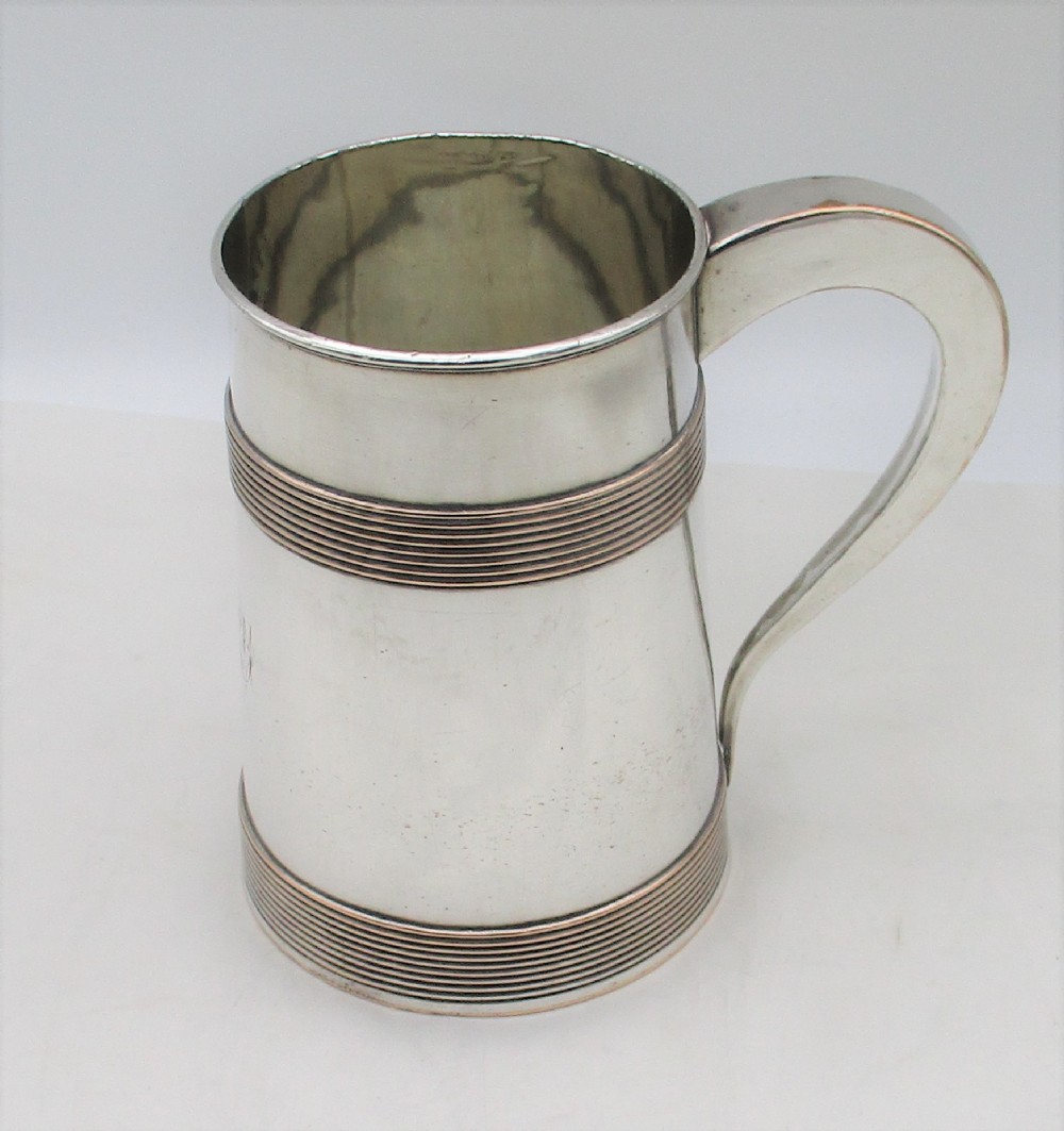 A Georgian Old Sheffield silver-plated quart tankard featuring a tapered body with reeded copper bands and a curved handle.