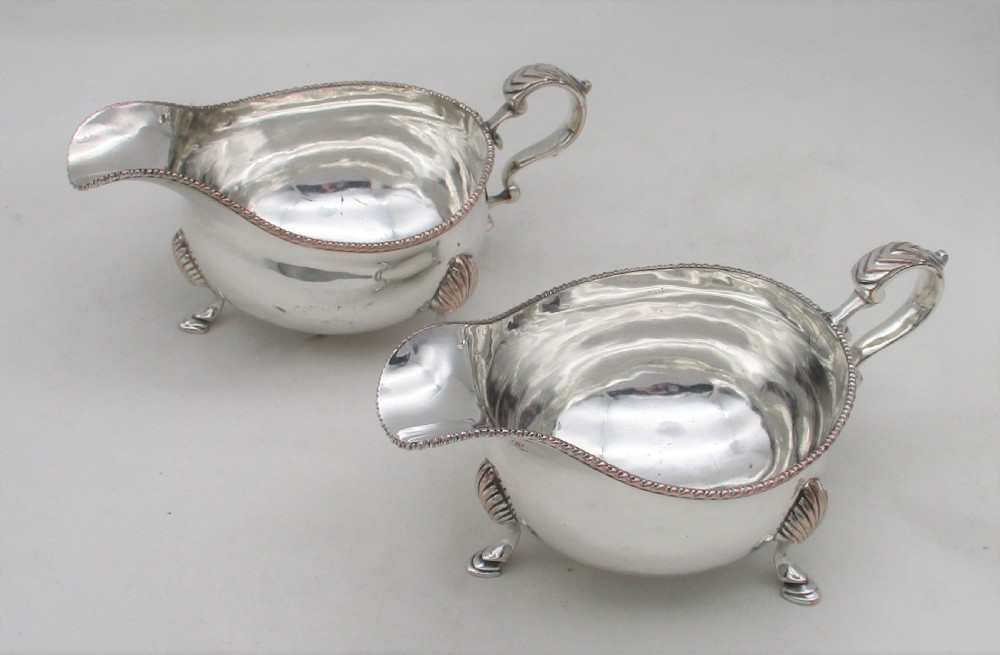 A pair of silver-plated sauce boats featuring double-scroll handles, gadrooned rims, and shell-capped feet. View VII