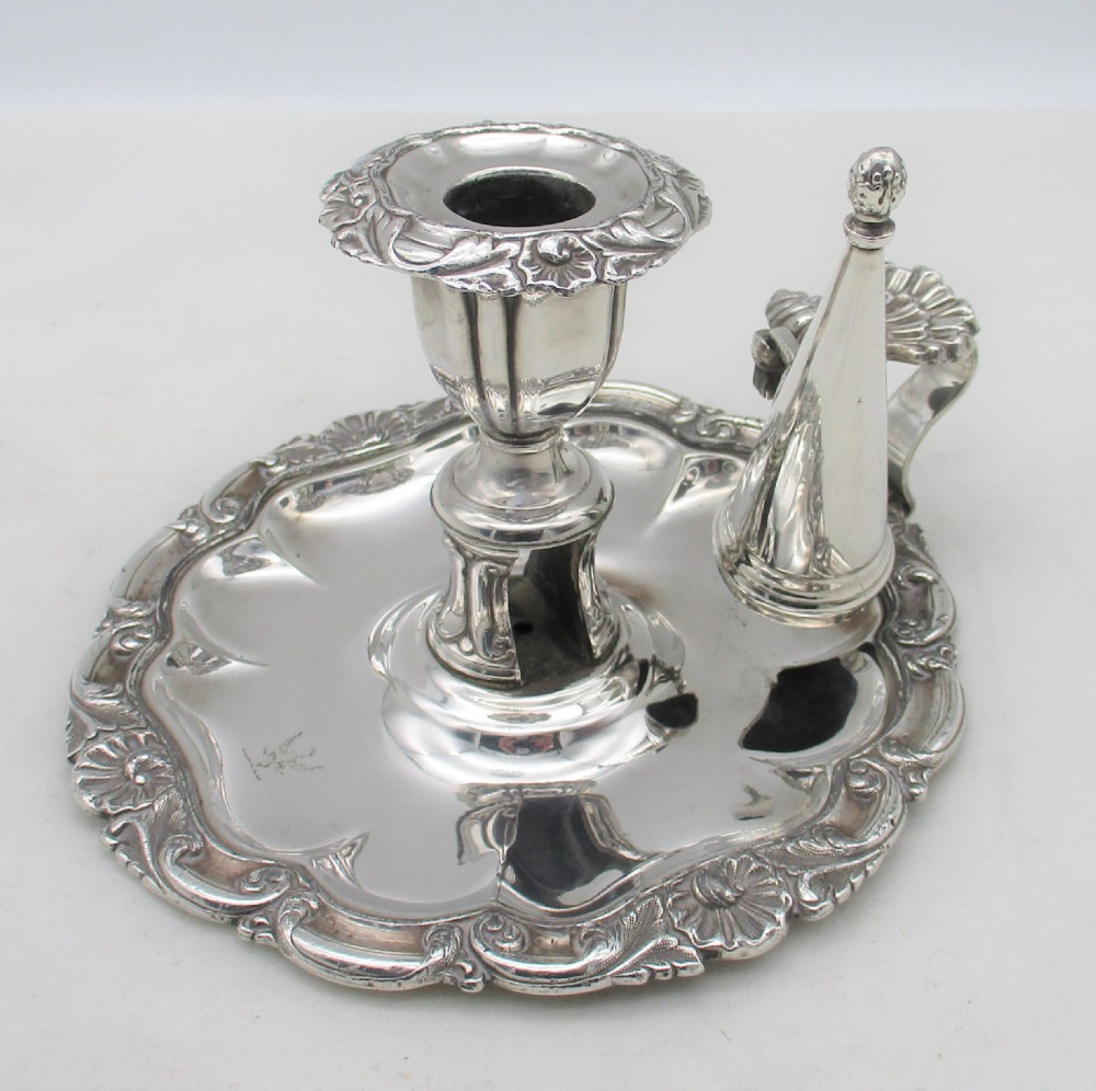 A 19th-century silver-plated chamber stick featuring a scalloped rim, central sconce, engraved crest on the dish, and a fitted conical snuffer.