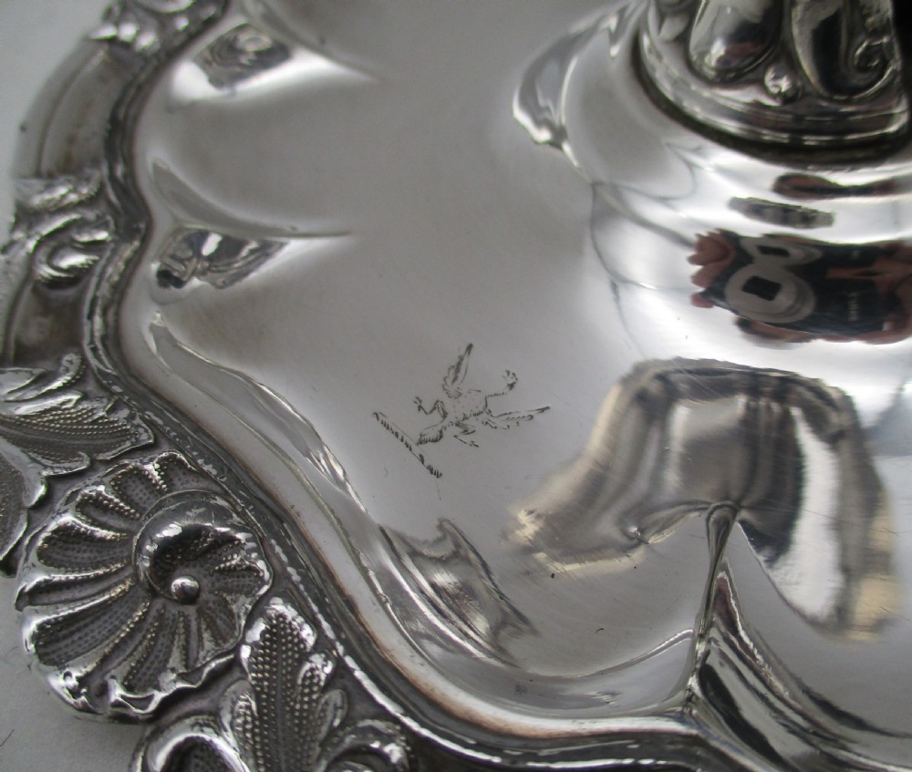 A 19th-century silver-plated chamber stick featuring a scalloped rim, central sconce, engraved crest on the dish, and a fitted conical snuffer. View II