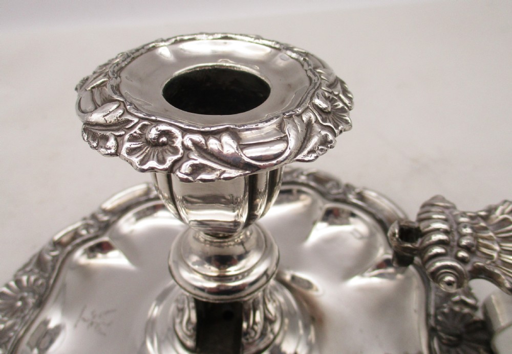 A 19th-century silver-plated chamber stick featuring a scalloped rim, central sconce, engraved crest on the dish, and a fitted conical snuffer. View IX