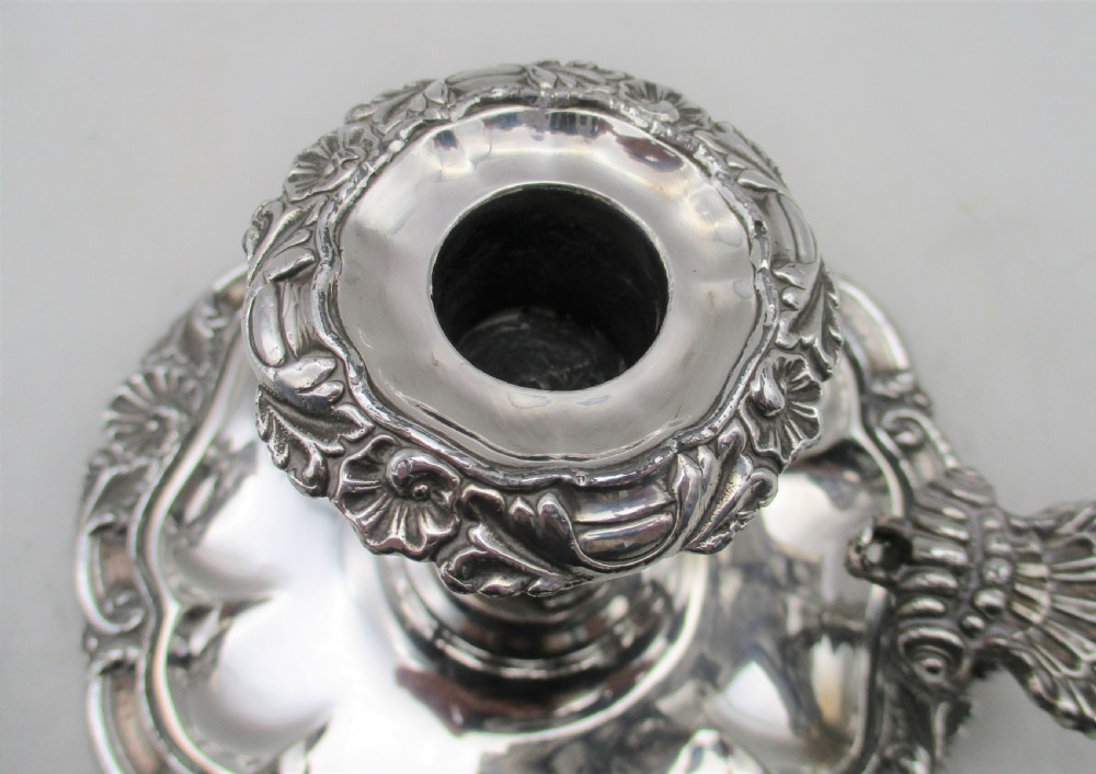 A 19th-century silver-plated chamber stick featuring a scalloped rim, central sconce, engraved crest on the dish, and a fitted conical snuffer. View X