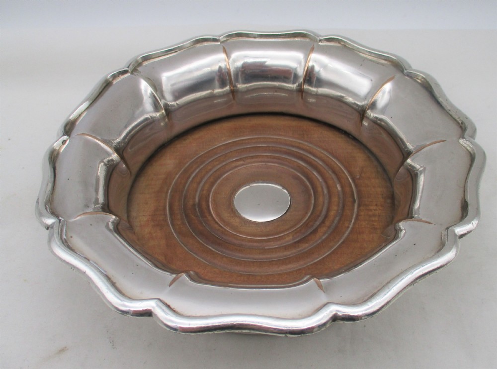 A set of three silver-plated wine bottle coasters with scalloped rims and turned wood bases. View VI