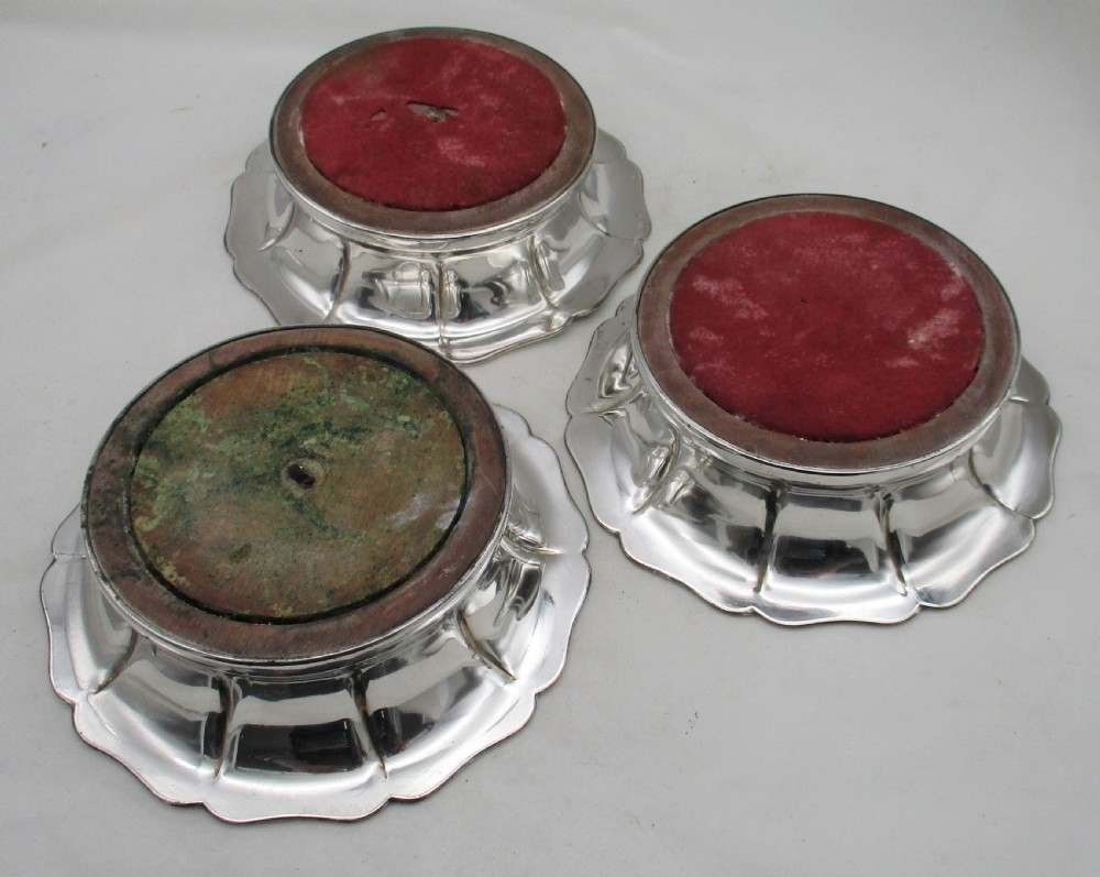 A set of three silver-plated wine bottle coasters with scalloped rims and turned wood bases. View VIII