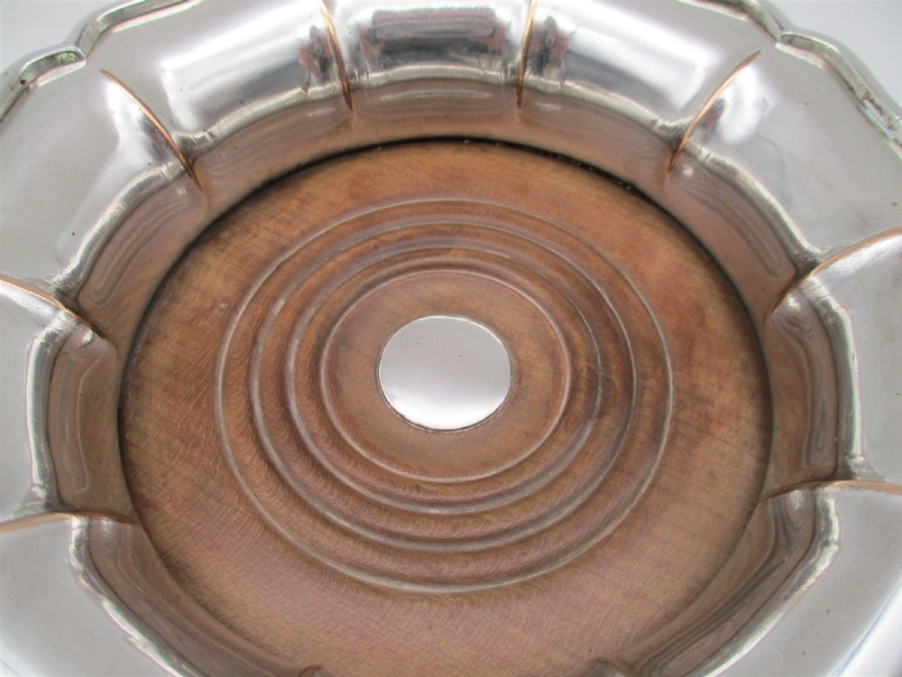 A set of three silver-plated wine bottle coasters with scalloped rims and turned wood bases. View IX