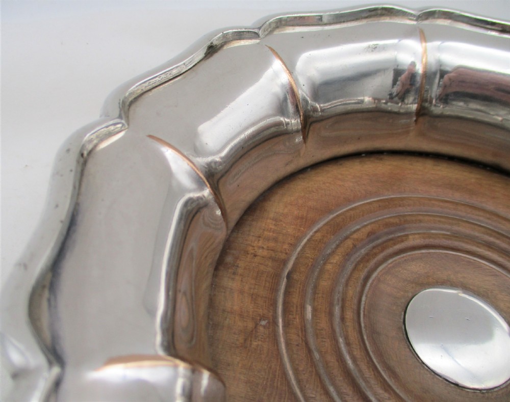 A set of three silver-plated wine bottle coasters with scalloped rims and turned wood bases. View X