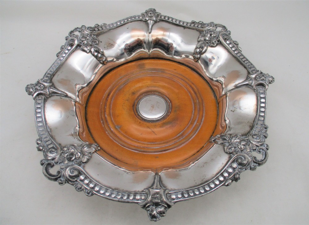 A pair of circular Regency silver-plated decanter coasters featuring turned wooden bases, central silver bosses, and ornate shell and scroll borders. View III