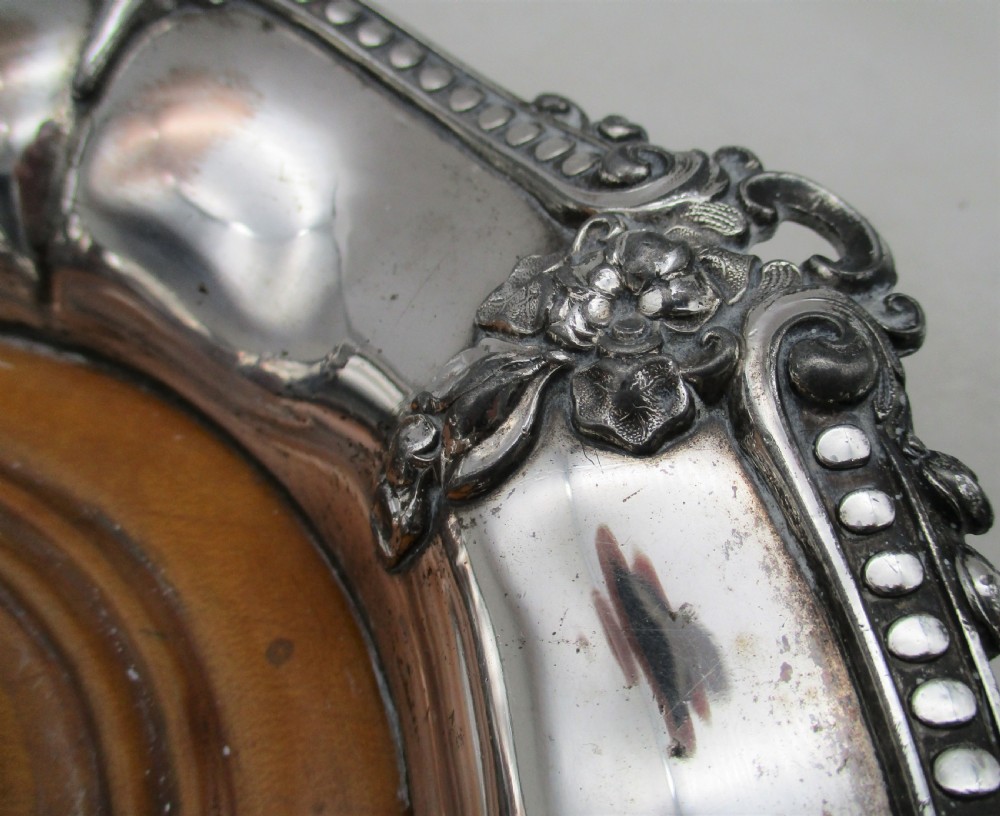 A pair of circular Regency silver-plated decanter coasters featuring turned wooden bases, central silver bosses, and ornate shell and scroll borders. View IX