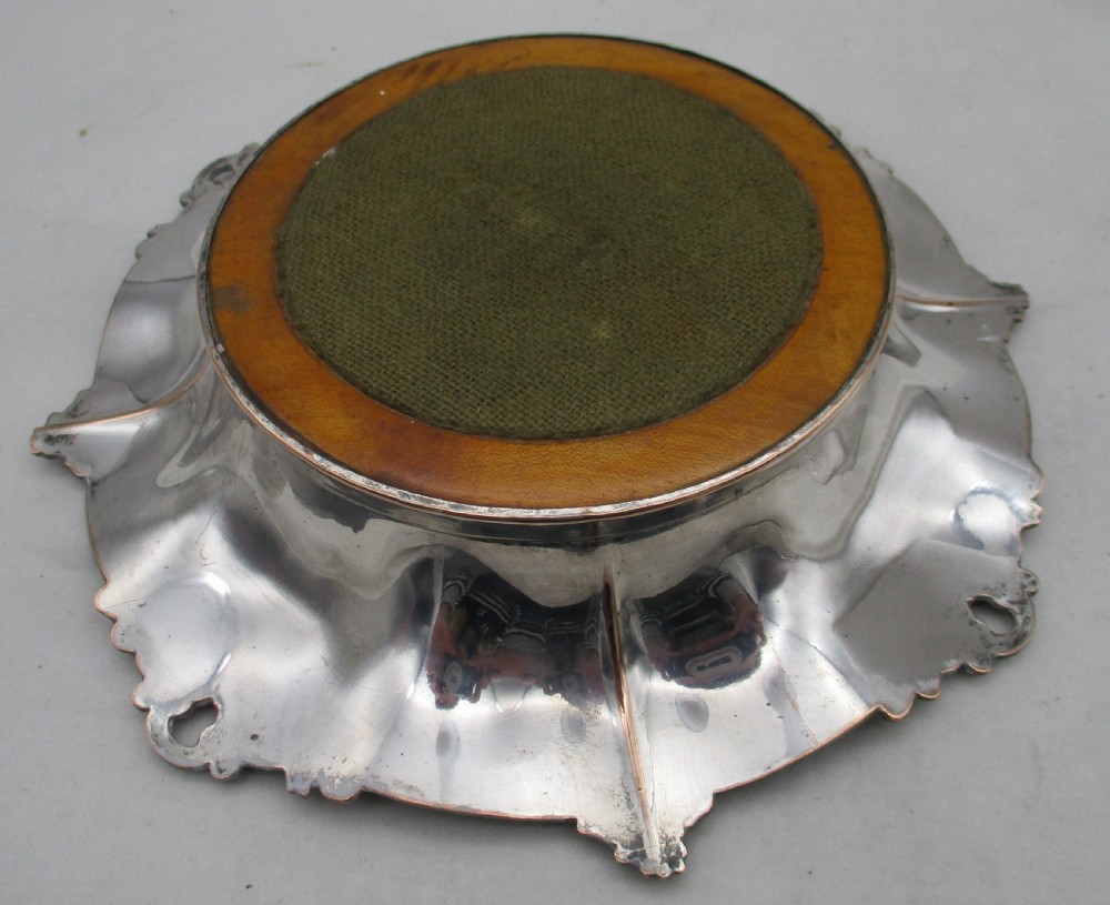 A pair of circular Regency silver-plated decanter coasters featuring turned wooden bases, central silver bosses, and ornate shell and scroll borders. View X