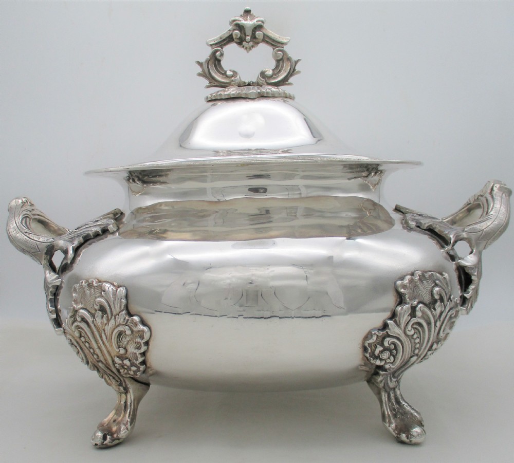 A large 19th-century silver-plated soup tureen featuring leaf-form handles, a domed lid with a scroll finial, and four scroll feet. View II