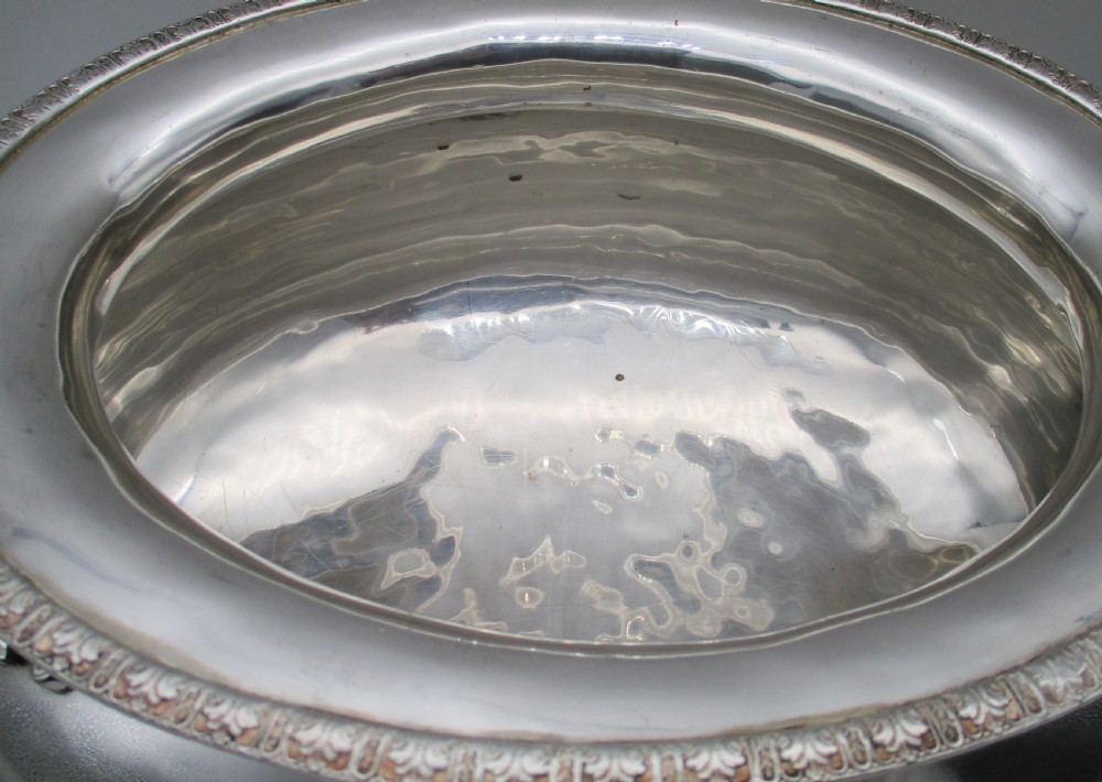 A large 19th-century silver-plated soup tureen featuring leaf-form handles, a domed lid with a scroll finial, and four scroll feet. View V