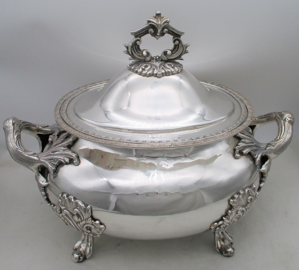 A large 19th-century silver-plated soup tureen featuring leaf-form handles, a domed lid with a scroll finial, and four scroll feet. View X
