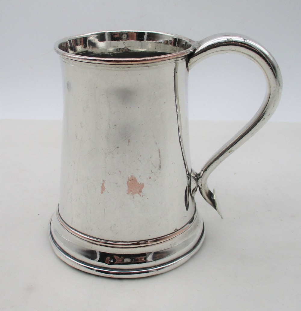 An 18th-century silver-plated pint tankard with a tapered body, curved strap handle, and a stepped circular base. View II