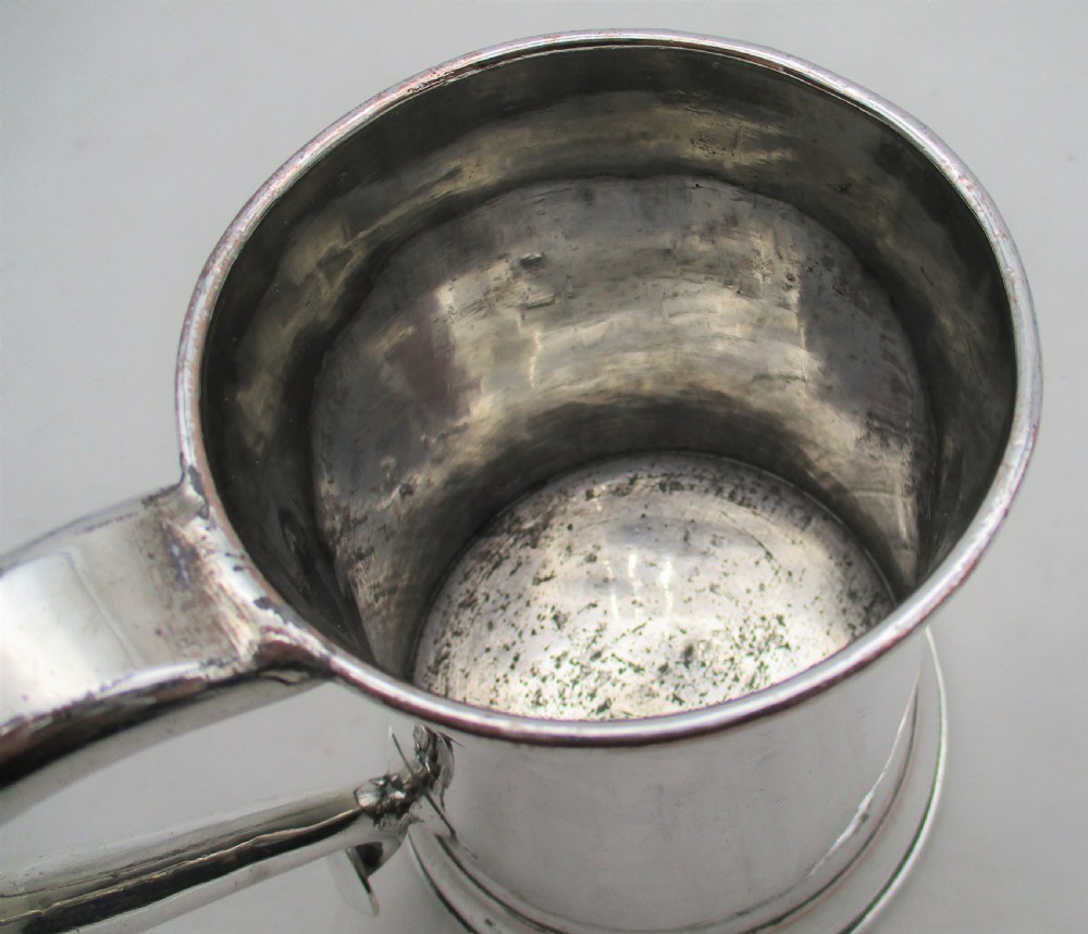 An 18th-century silver-plated pint tankard with a tapered body, curved strap handle, and a stepped circular base. View V