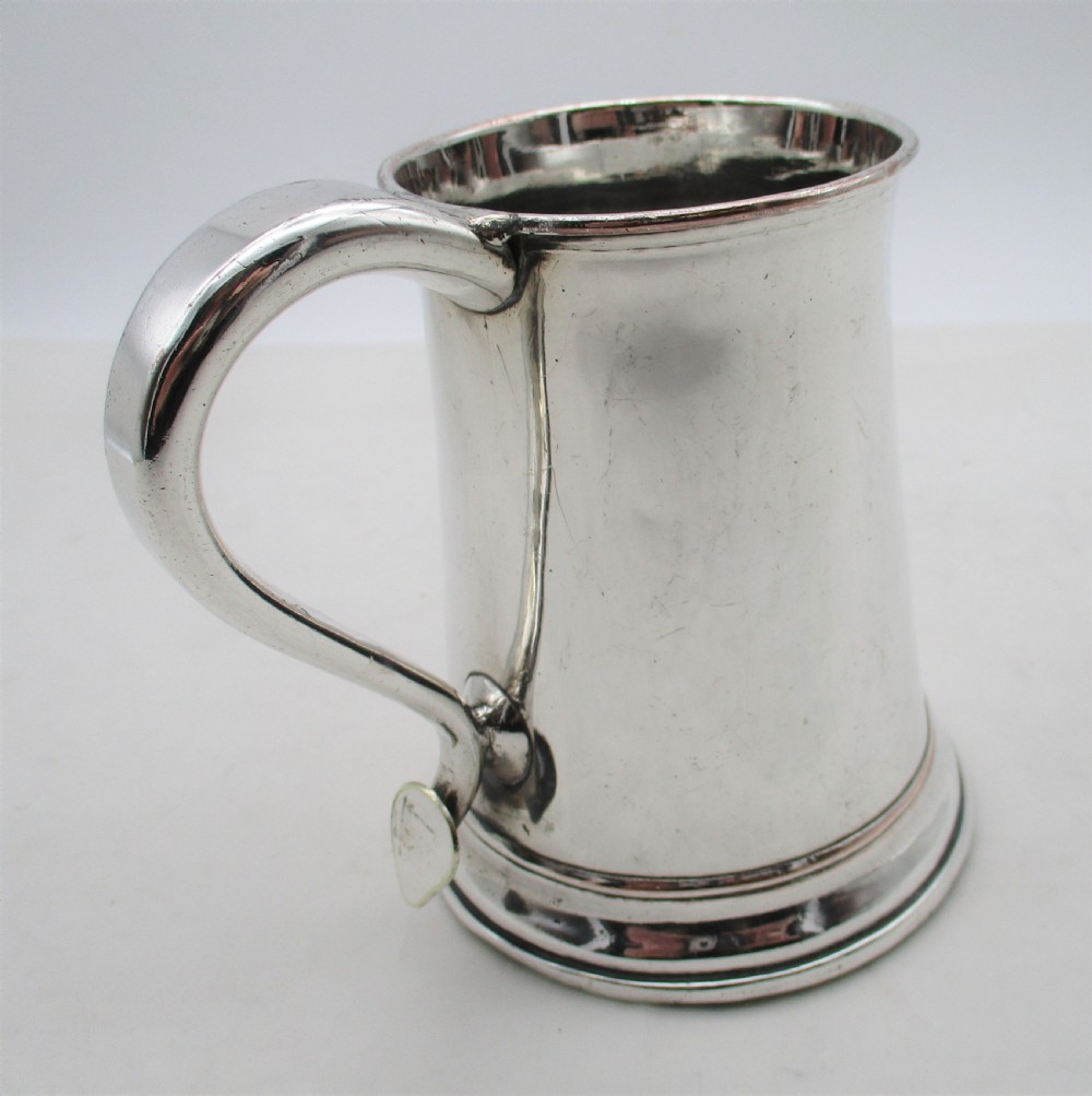 An 18th-century silver-plated pint tankard with a tapered body, curved strap handle, and a stepped circular base. View VI