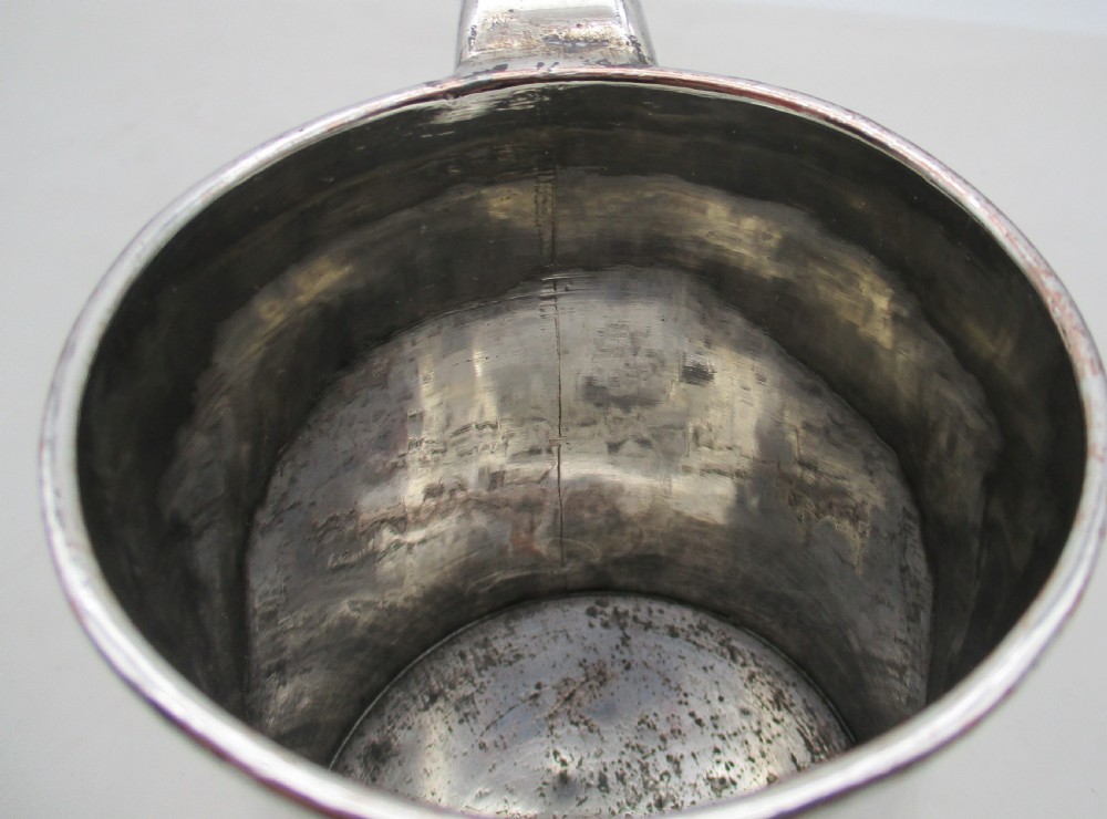 An 18th-century silver-plated pint tankard with a tapered body, curved strap handle, and a stepped circular base. View VIII