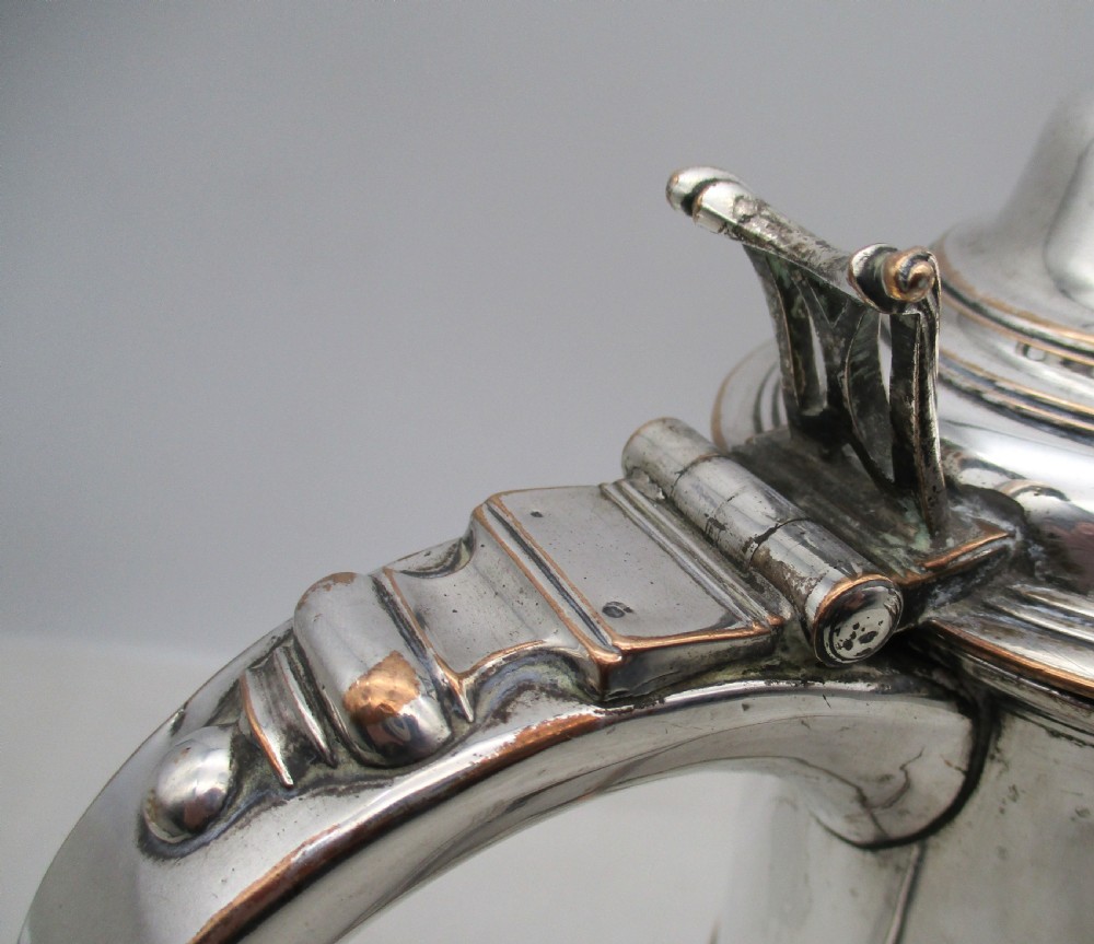 An 18th-century Old Sheffield plated silver quart tankard featuring a domed lid, thumbpiece, scroll handle, and visible copper bleeding along the moulded edges. View V