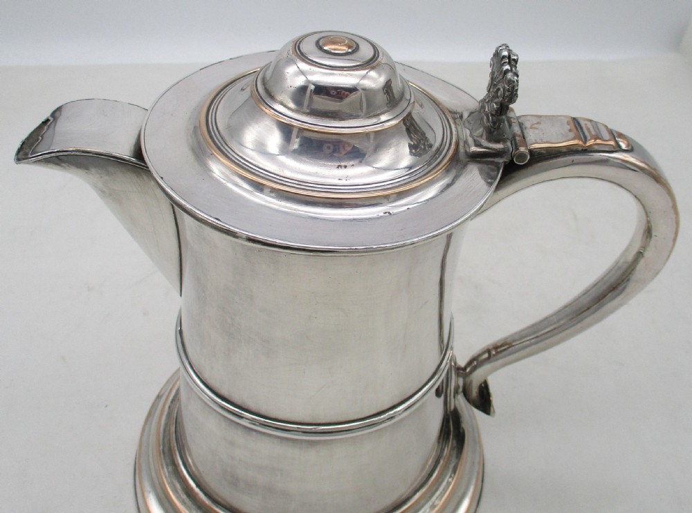 A Georgian silver-plated beer jug featuring a hinged stepped lid, flared base, and curved handle with faint copper oxidisation visible along the edges. View II