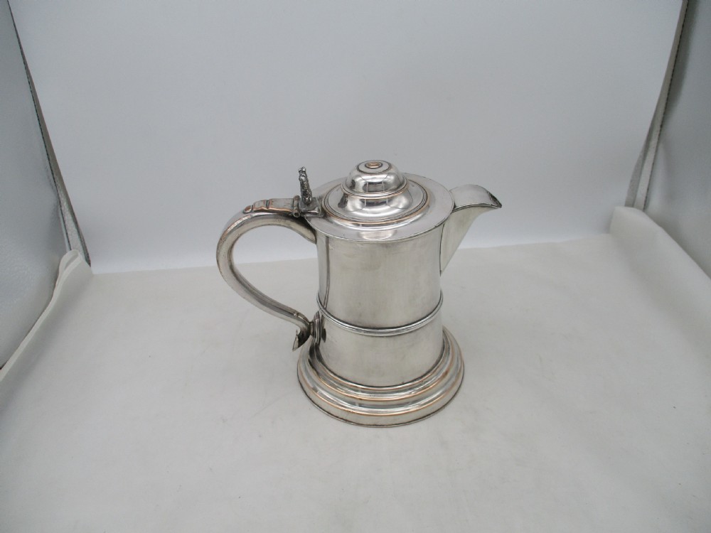 A Georgian silver-plated beer jug featuring a hinged stepped lid, flared base, and curved handle with faint copper oxidisation visible along the edges. View IV