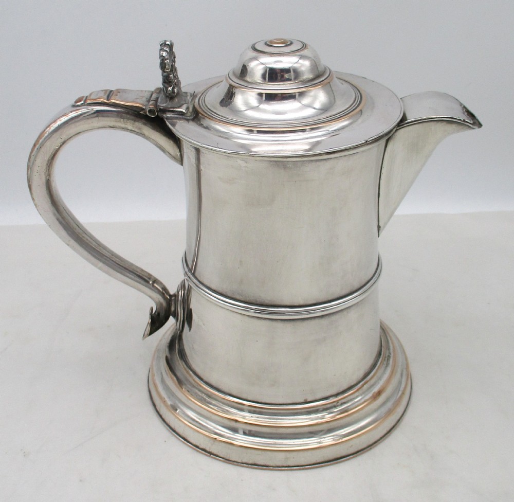 A Georgian silver-plated beer jug featuring a hinged stepped lid, flared base, and curved handle with faint copper oxidisation visible along the edges. View V