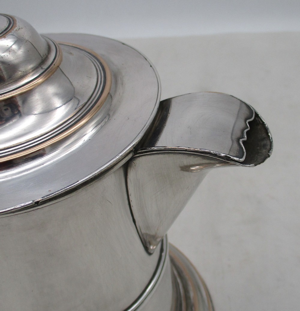A Georgian silver-plated beer jug featuring a hinged stepped lid, flared base, and curved handle with faint copper oxidisation visible along the edges. View IX