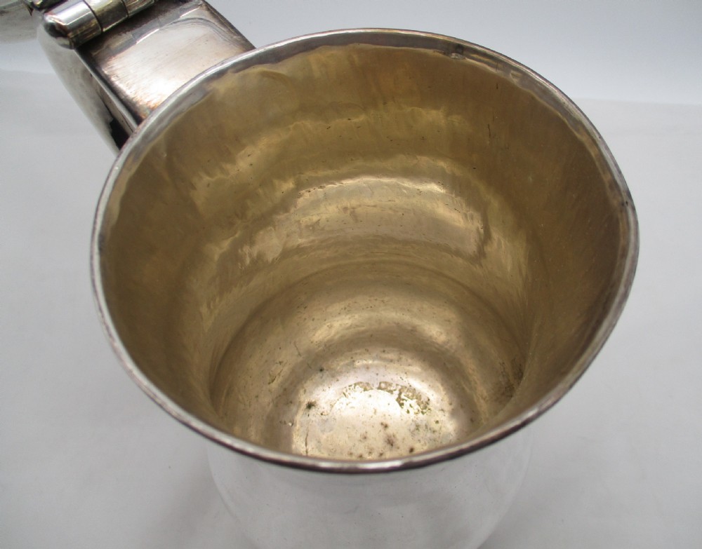 A Georgian silver-plated lidded tankard featuring a baluster-shaped body, a stepped domed lid with a hinge, and a curved scroll handle. View III