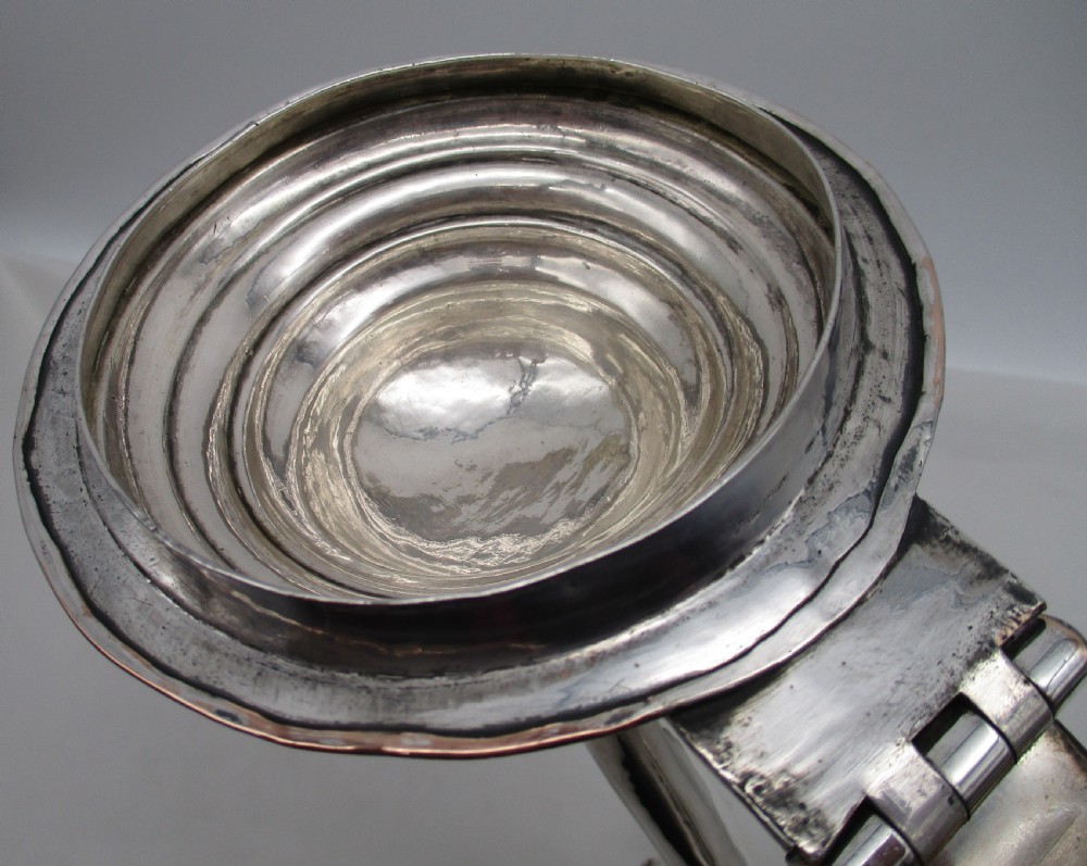 A Georgian silver-plated lidded tankard featuring a baluster-shaped body, a stepped domed lid with a hinge, and a curved scroll handle. View IV