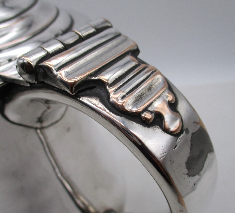 A Georgian silver-plated lidded tankard featuring a baluster-shaped body, a stepped domed lid with a hinge, and a curved scroll handle. View VI