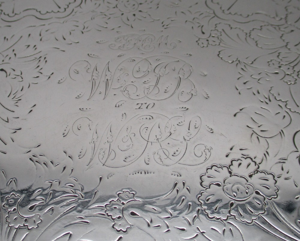 A circular silver-plated tray featuring engraved scrollwork across the surface and a raised border decorated with molded grapevine and foliage motifs. View IV