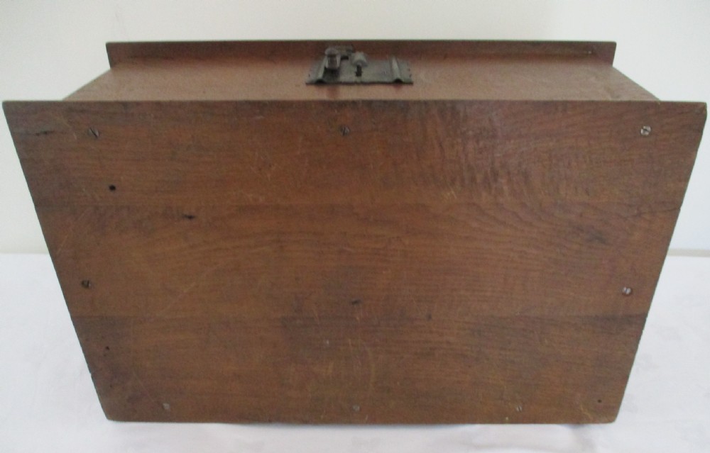 A rectangular carved oak box featuring a flat hinged lid with a carved central lozenge motif, carved borders, and a dark iron lock plate on the front panel. View III