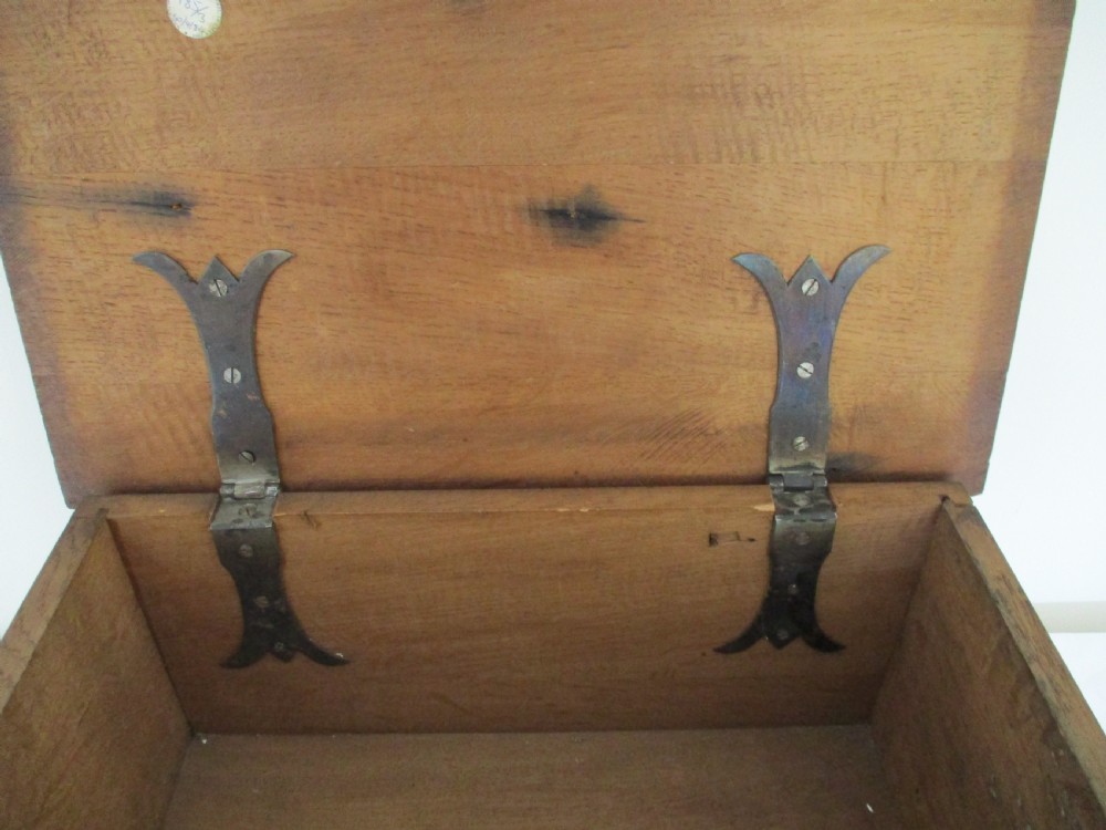 A rectangular carved oak box featuring a flat hinged lid with a carved central lozenge motif, carved borders, and a dark iron lock plate on the front panel. View V