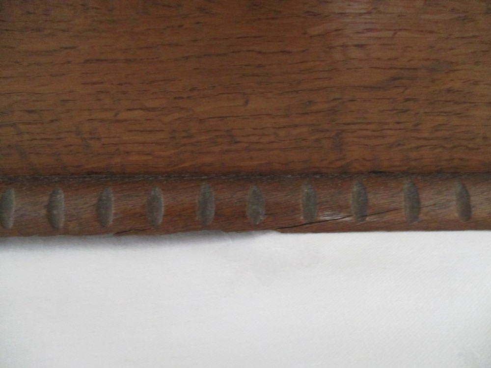 A rectangular carved oak box featuring a flat hinged lid with a carved central lozenge motif, carved borders, and a dark iron lock plate on the front panel. View X