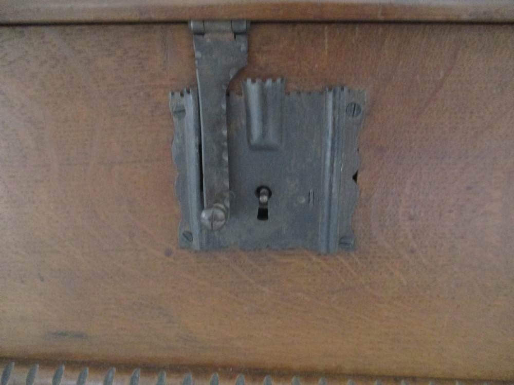 A rectangular carved oak box featuring a flat hinged lid with a carved central lozenge motif, carved borders, and a dark iron lock plate on the front panel. View XI