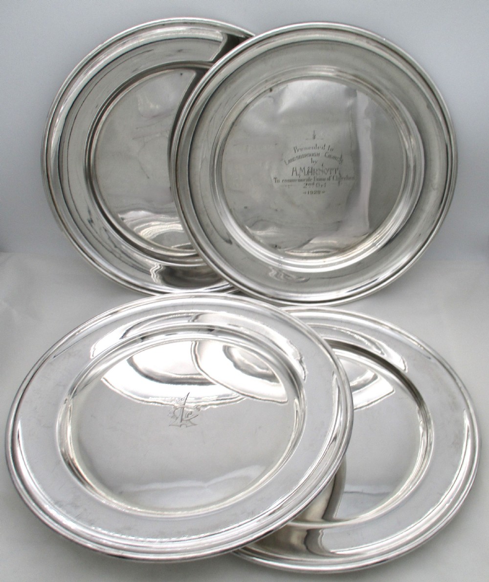 A set of four circular silver plated charger plates featuring wide flat rims and engraved central inscriptions and monograms. View III