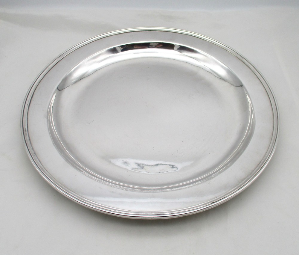A pair of circular 14-inch silver-plated charger plates with polished central wells and simple reeded rims. View II