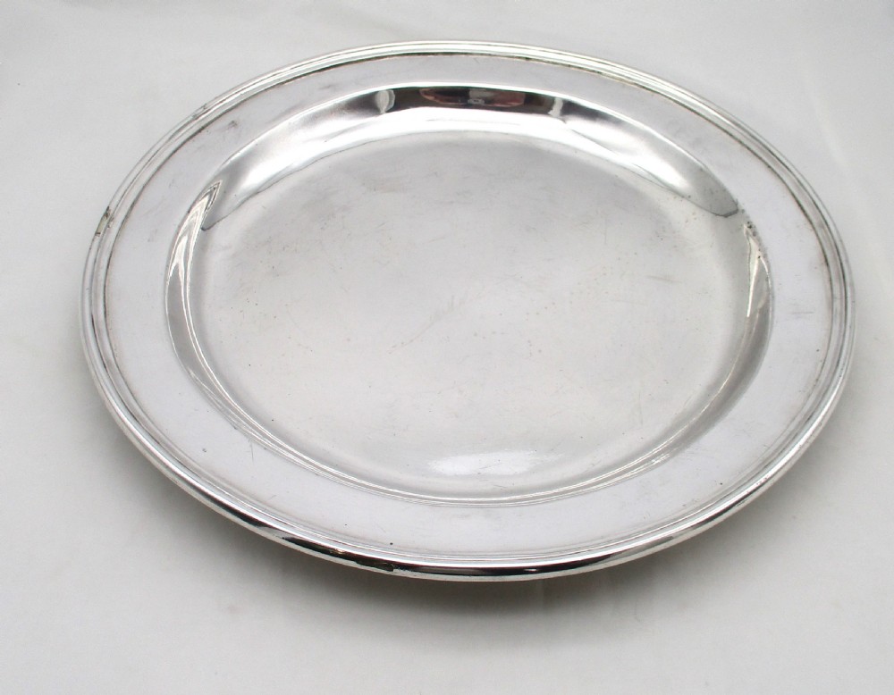 A pair of circular 14-inch silver-plated charger plates with polished central wells and simple reeded rims. View V