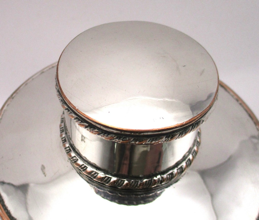 A circular Regency Old Sheffield plated tea caddy featuring a cylindrical silver body with gadrooned rope-twist borders and a fitted cap lid. View III