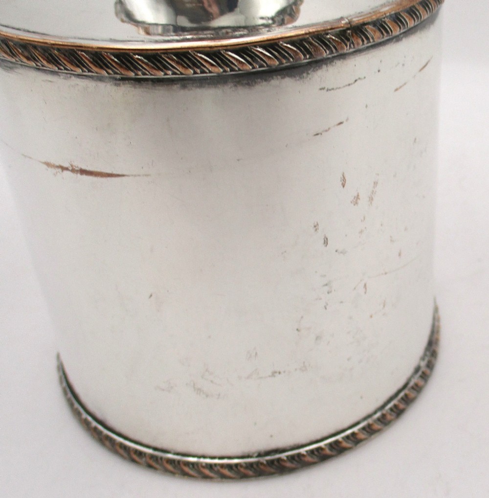 A circular Regency Old Sheffield plated tea caddy featuring a cylindrical silver body with gadrooned rope-twist borders and a fitted cap lid. View VI