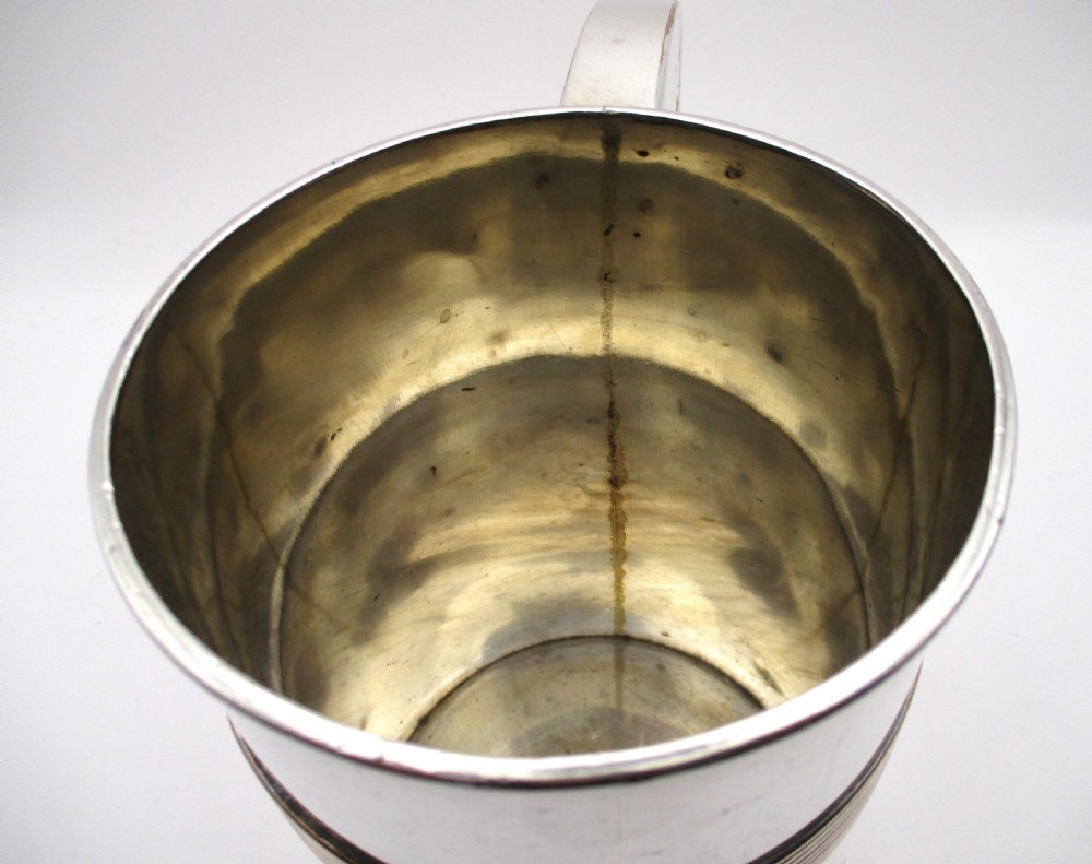 A cylindrical Georgian Sheffield plated silver tankard featuring horizontal reeded bands, an engraved monogram, and a polished loop handle. View IV