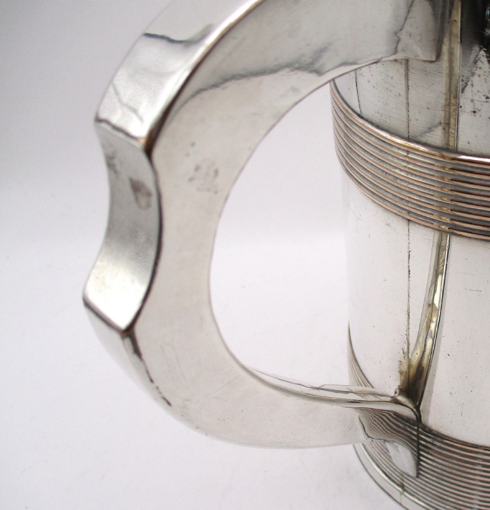 A cylindrical Georgian Sheffield plated silver tankard featuring horizontal reeded bands, an engraved monogram, and a polished loop handle. View VI