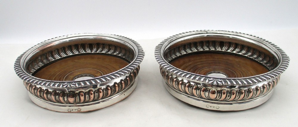 A pair of Georgian Old Sheffield Plated wine coasters featuring turned wooden bases with silver central bosses and gadrooned metal rims. View II