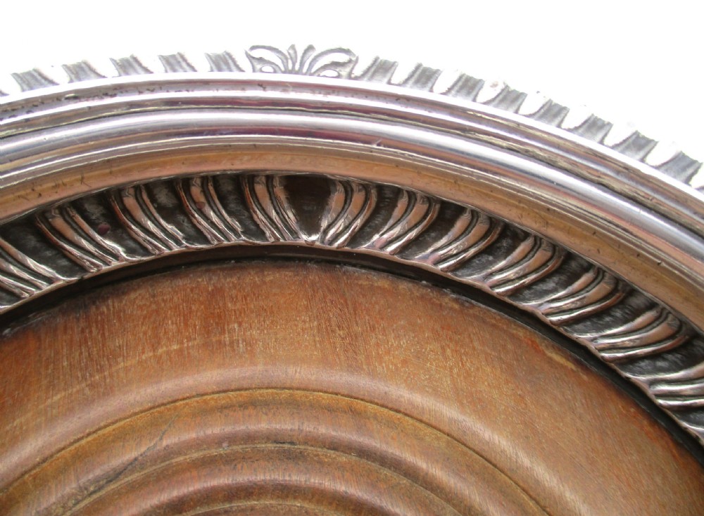 A pair of Georgian Old Sheffield Plated wine coasters featuring turned wooden bases with silver central bosses and gadrooned metal rims. View VI