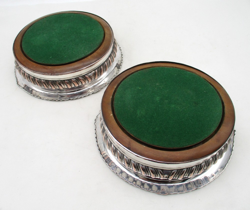 A pair of Georgian Old Sheffield Plated wine coasters featuring turned wooden bases with silver central bosses and gadrooned metal rims. View IX