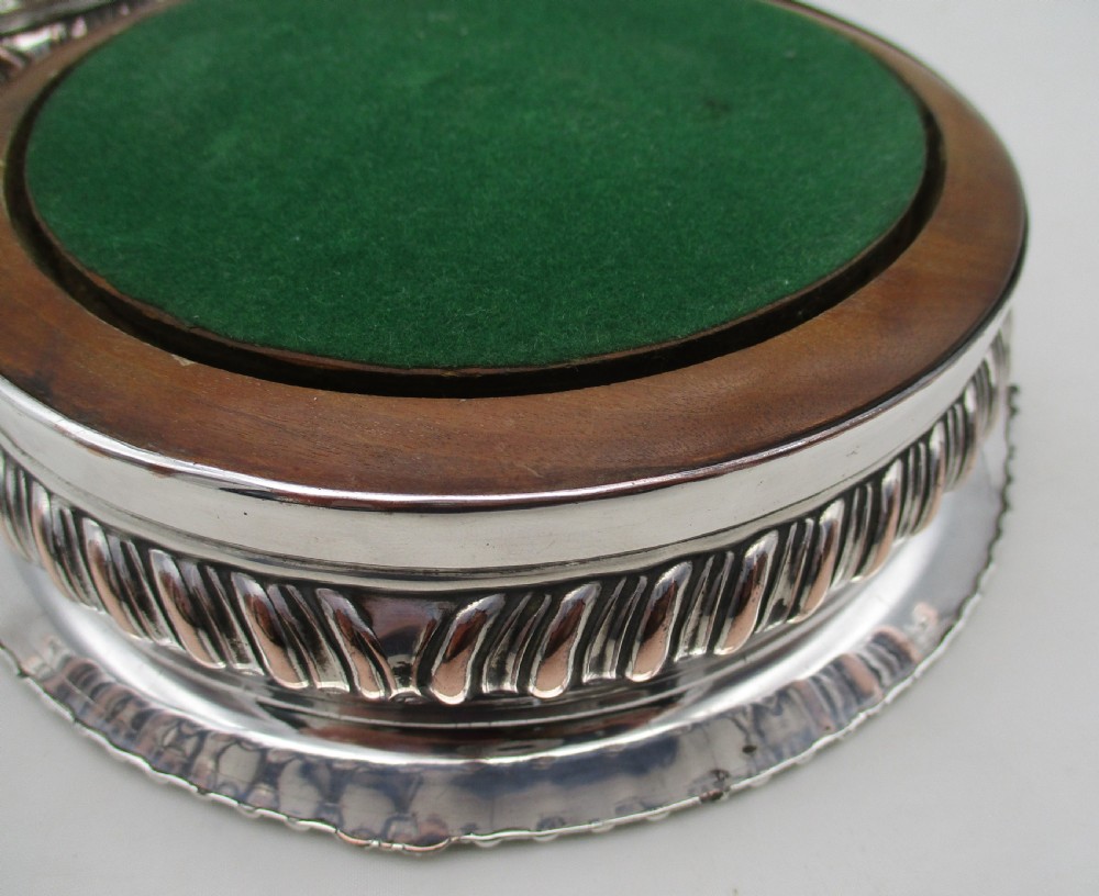 A pair of Georgian Old Sheffield Plated wine coasters featuring turned wooden bases with silver central bosses and gadrooned metal rims. View X