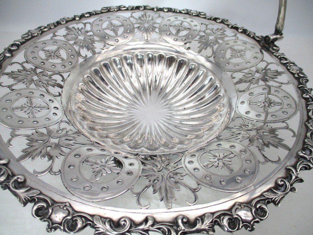 A nineteenth-century circular silver-plated cake basket featuring an arched swing handle, pierced foliate border, and fluted dish. View III