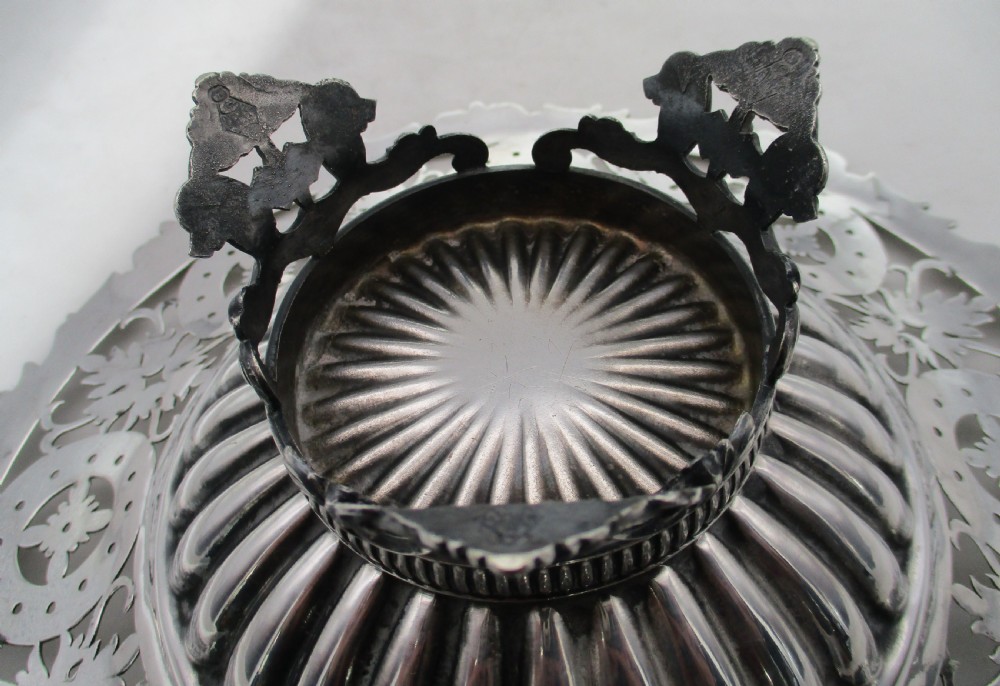 A nineteenth-century circular silver-plated cake basket featuring an arched swing handle, pierced foliate border, and fluted dish. View VII