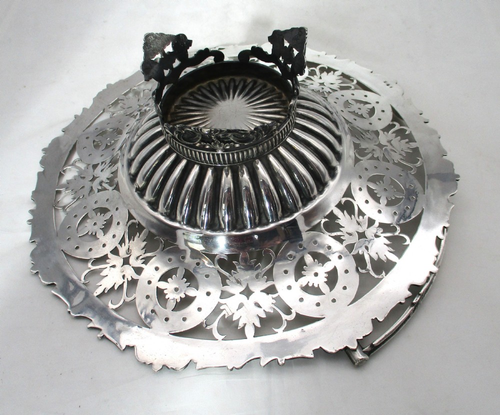 A nineteenth-century circular silver-plated cake basket featuring an arched swing handle, pierced foliate border, and fluted dish. View IX