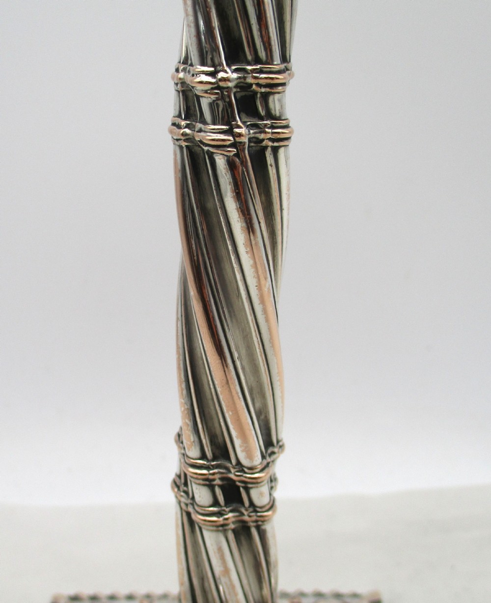 A pair of silver-plated taper candlesticks featuring spiral-fluted columns, foliage capitals, and decorative square bases. View V