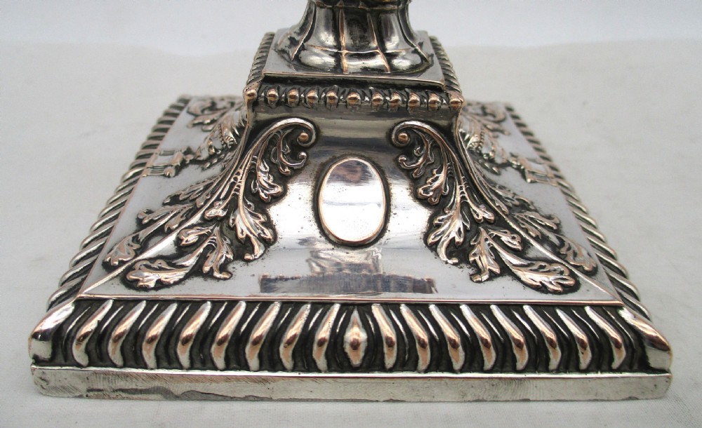 A pair of silver-plated taper candlesticks featuring spiral-fluted columns, foliage capitals, and decorative square bases. View VI